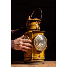 a person holding onto an old yellow fire hydrant with its light on it's side