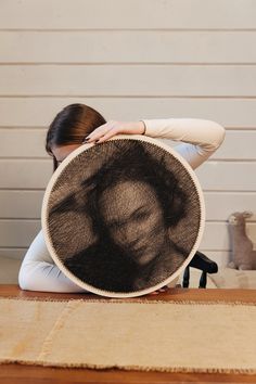 a woman sitting on the floor with her back to the camera and covering her face