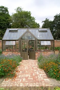 a brick walkway leads to a small greenhouse