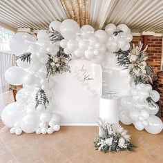 balloons and greenery are on display in front of a white backdrop at a wedding