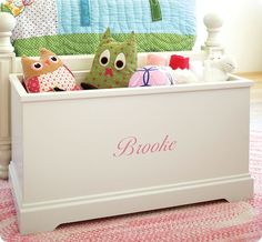 two stuffed animals sitting in a white toy box on a pink and white carpeted floor