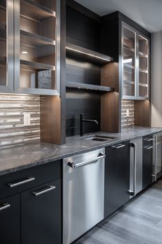 an empty kitchen with stainless steel appliances and black cabinetry, along with marble counter tops