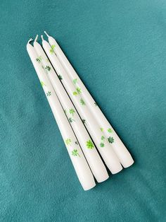 four st patrick's day drinking straws sitting on a green surface with shamrock leaves