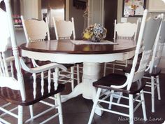 a dining room table with white chairs and a vase on it's centerpiece