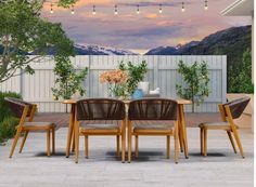 an outdoor dining table and chairs with mountains in the background