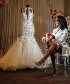 a woman sitting on a chair in front of a wedding dress and flower bouquets