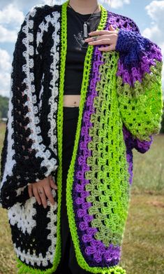 a woman is wearing a crocheted cardigan and holding her hand on her hip