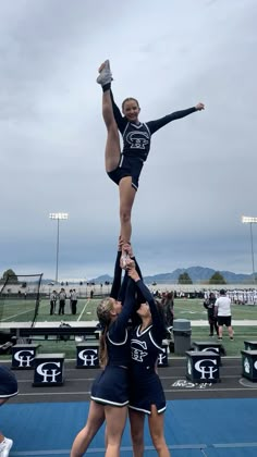 two cheerleaders doing tricks on the sidelines