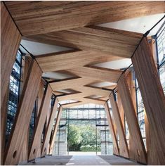 the inside of a building with wooden beams and glass windows on each side, along with concrete flooring