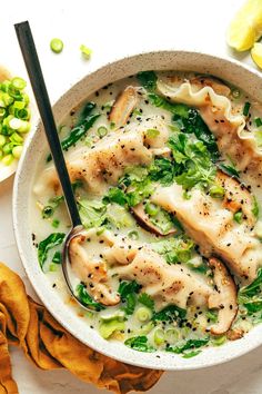 a white bowl filled with chicken and broccoli soup next to sliced lemons