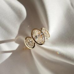 three diamond earrings sitting on top of a white cloth