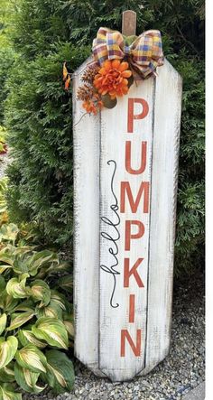 a wooden sign that says pumpkin and has a bow on it's head in front of some bushes