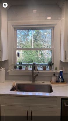 a kitchen sink sitting under a window next to a counter