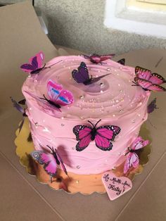 a pink cake with butterflies on it in a box