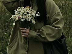 a woman holding a bouquet of daisies in her hand and covering her face with both hands