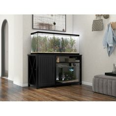 a fish tank sitting on top of a black cabinet in a living room next to a couch