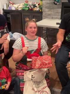 a group of people sitting on the floor with presents in front of them and one person holding a bag