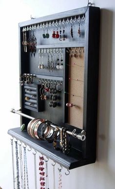 a wall mounted jewelry organizer with lots of necklaces and earrings hanging on it's sides