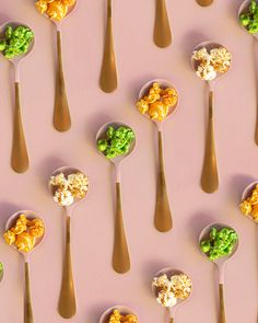 spoons filled with different types of food on top of a pink surface, including broccoli and cauliflower