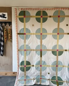 a quilt hanging on a wall next to a coat rack