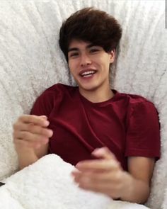 a young man laying in bed and smiling