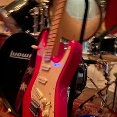 a red guitar sitting on top of a drum kit