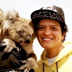 a man holding a koala in his arms and wearing a hat with writing on it