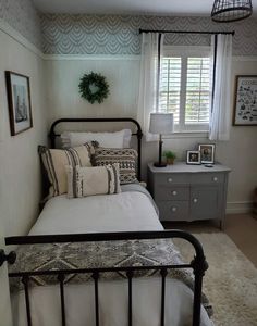 a bed sitting in a bedroom next to a window with blinds on the windowsill