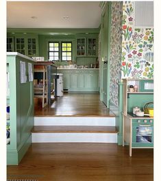 a kitchen with green walls and white stairs leading up to the upper floor, along with wooden floors