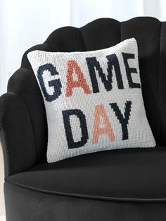 a black chair with a pillow that says game day on it and an orange lettering