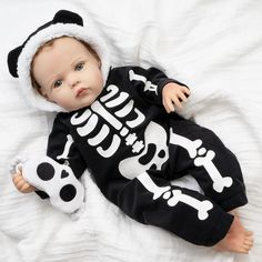 a baby doll laying on top of a white blanket wearing a black and white outfit