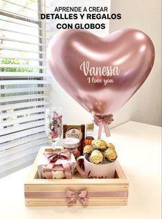 a pink heart shaped balloon sitting on top of a wooden box filled with chocolates