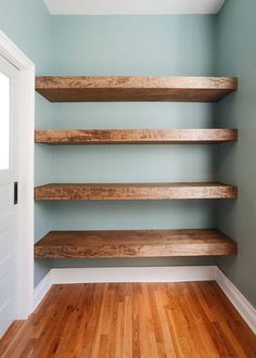 empty shelves in the corner of a room with wood floors and hard wood flooring