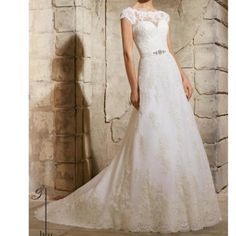 a woman in a wedding dress standing next to a stone wall