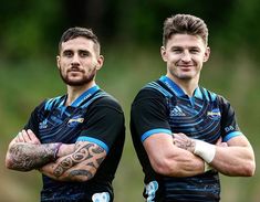 two rugby players are standing with their arms crossed