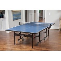 a ping pong table in the middle of a living room with hard wood floors