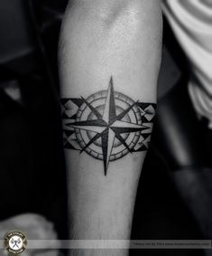 a black and white photo of a compass tattoo on the left arm with an arrow in it