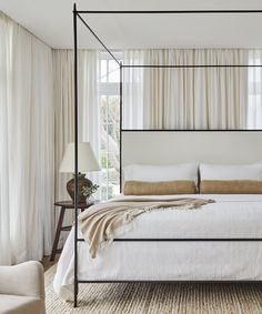 a bedroom with four poster bed and white curtains