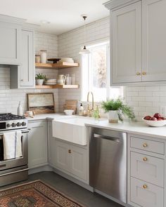 a kitchen with white cabinets and stainless steel appliances in the center, along with an area rug on the floor