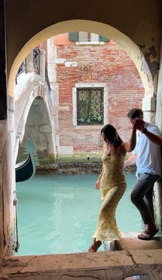 a man and woman standing next to each other near water