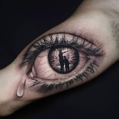 a man and woman standing in an eye tattoo on the left inner side of his arm