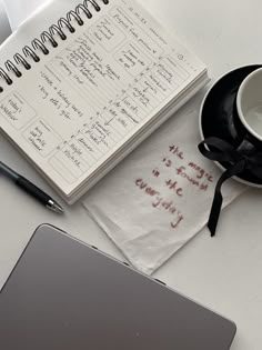 a notepad with writing on it next to a cup of coffee and a laptop