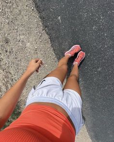 a woman standing on the side of a road with her feet up in the air