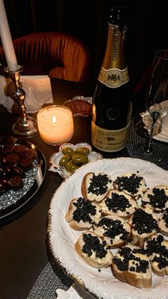 an assortment of appetizers on a plate with candles and wine in the background