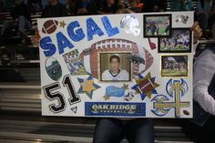 a man holding up a sign with pictures on it in the middle of a stadium