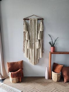 a wall hanging with tassels on it in a room next to a chair