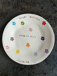 a white plate with colorful flowers and the words happy birthday written on it