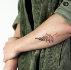 a woman's arm with a small fern tattoo on the left side of her arm