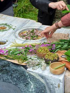 a group of people standing around a table filled with flowers and plants on top of it