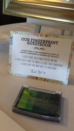 a sign that says our fingerprint guest book is next to a cell phone on a table